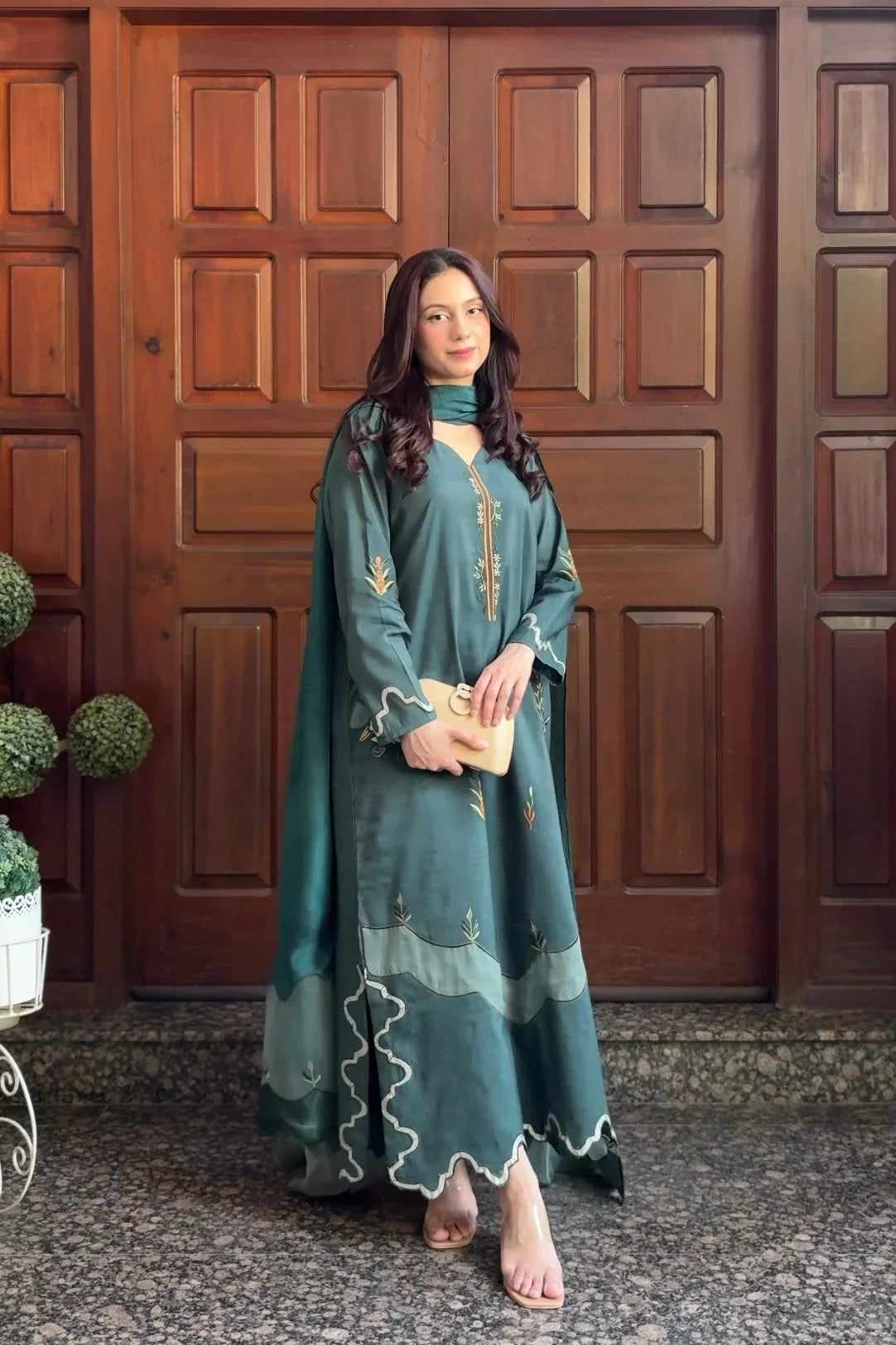 Woman in a teal dress standing in front of a wooden door